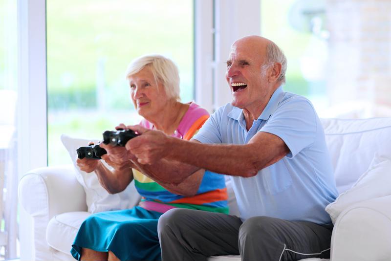 An elderly couple are playing a video game.
