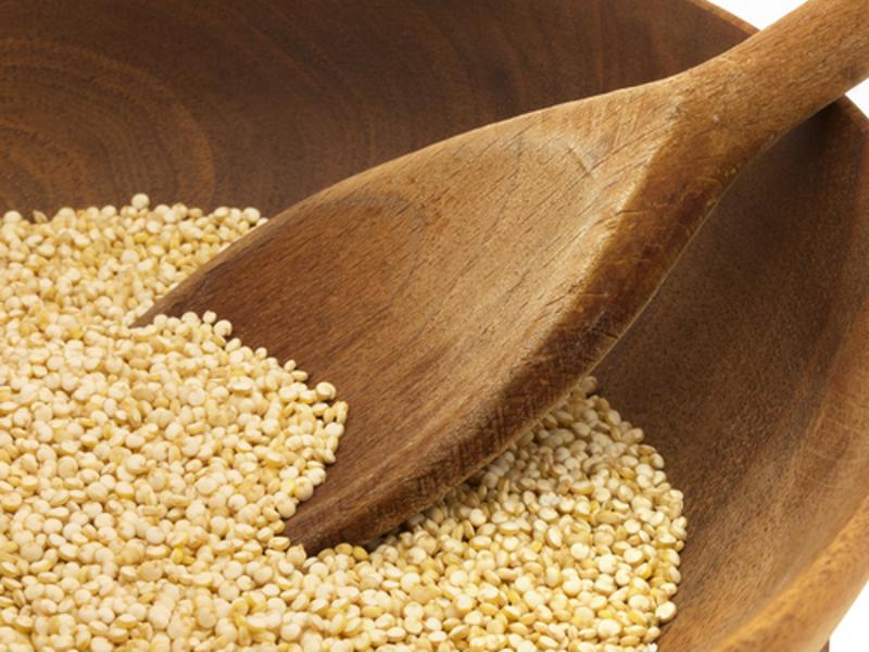 Raw quinoa with wooden spoon.