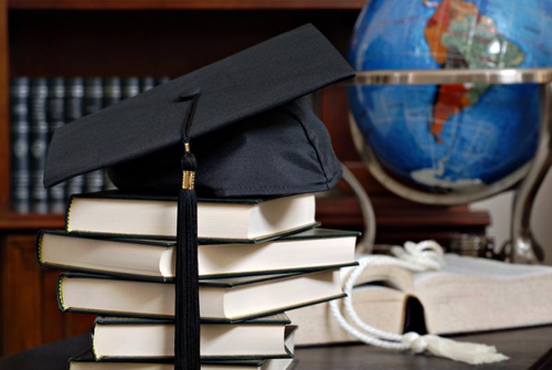 A college graduation cap on textbooks.