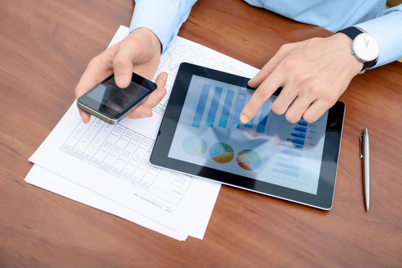 Office worker using a tablet and smartphone to review data.