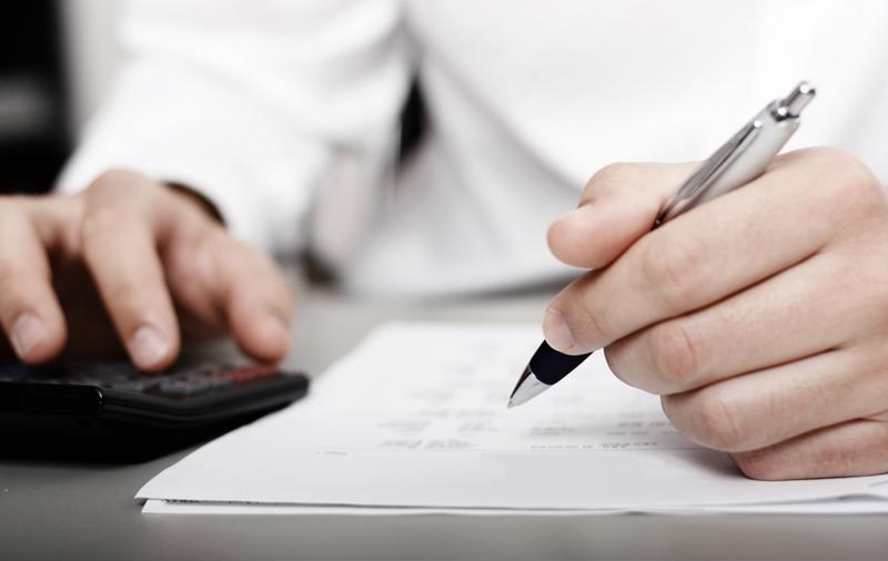 A male accountant with a document and a pen in his hand.
