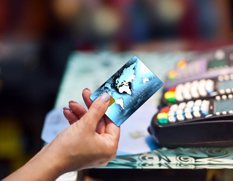 Consumer handing credit card with POS portals in the background. 