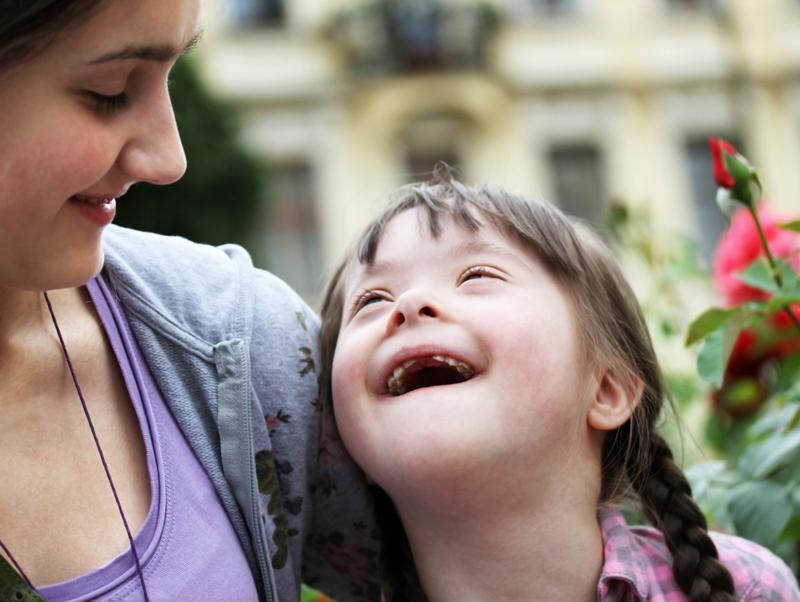 Girl who has Down syndrome smiling with mom.