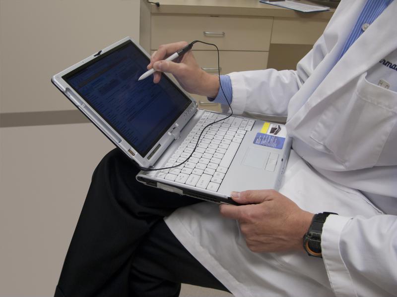 Doctor taking EMR notes on laptop.