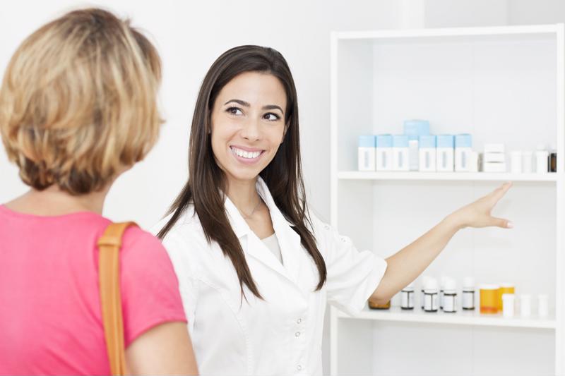 A woman picking up medication at a pharmacy.