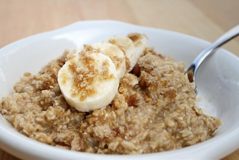 A bowl of oatmeal topped with brown sugar and bananas