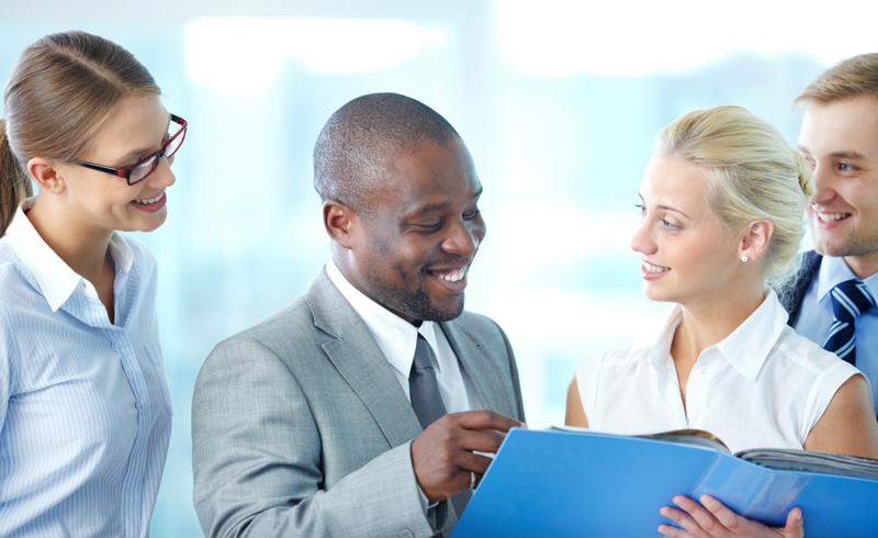 Four employees discussing a project while smiling and in good spirits