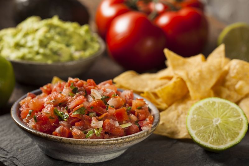 Salsa and guacamole on a table with chips