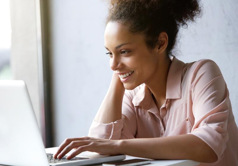 A happy woman looking at job listings on her computer.