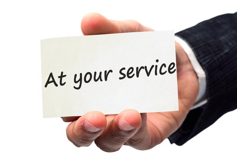 Business card that reads "At your service," held by a business person. 