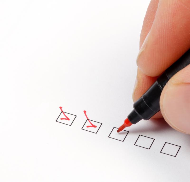 Person using red pen to check off boxes.