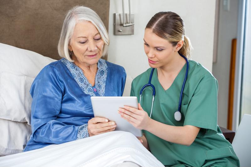 Nurse looking at tablet with senior patient.