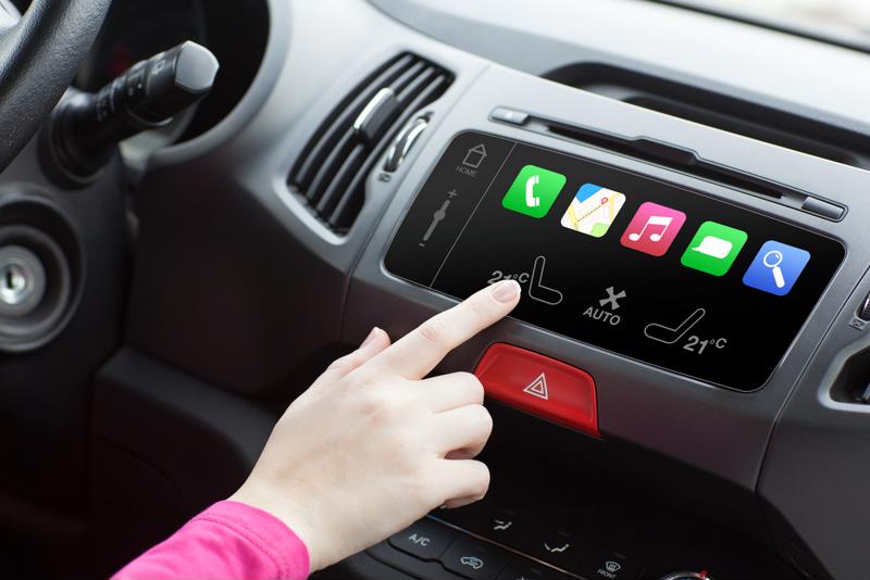 Drivers hand touching car dashboard featuring the phone, GPS, message, search and music app. 