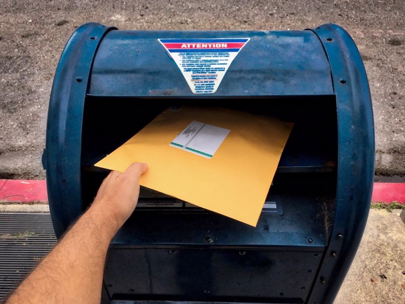 Mail is dropped into a mailbox.