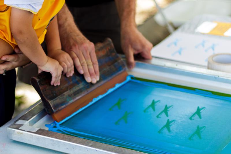 An adult and child create a screen print together.