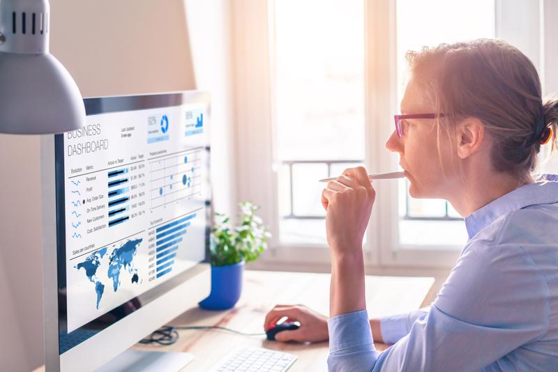 A woman sits looking at data on her computer