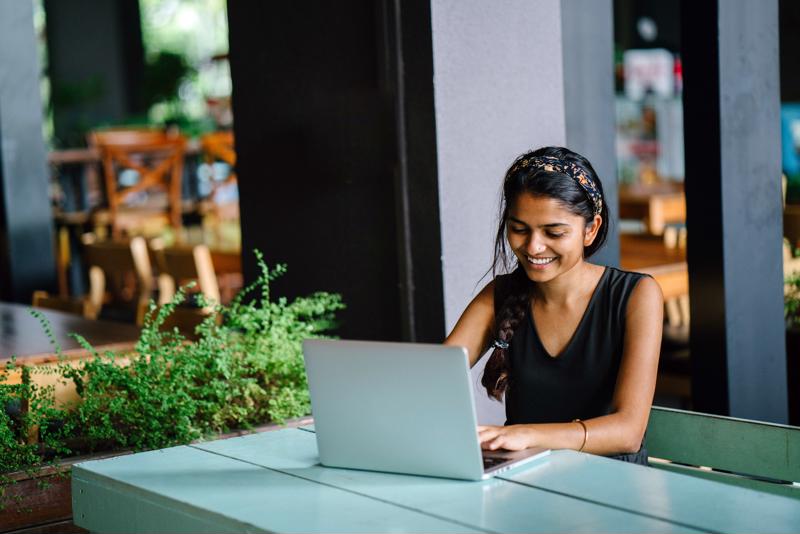 A remote worker collaborates happily with colleagues from behind a laptop.