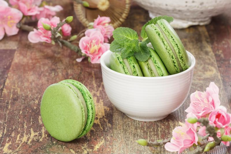A small bowl of matcha macarons sitting on a table.