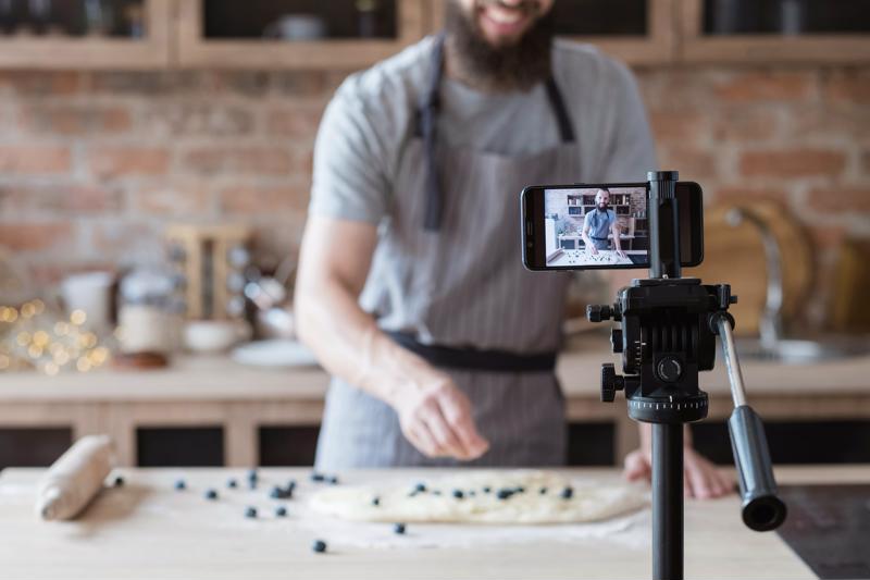 A chef filming himself as he prepares a dish.