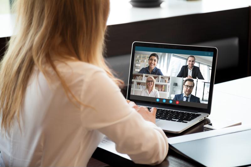 Woman participates in a four-way video conference from a laptop.