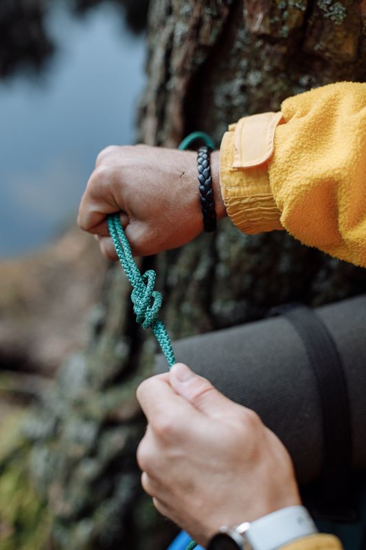 hands tying climbing rope on a cliff