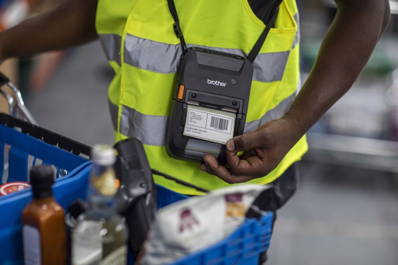 A warehouse worker with a portable printer printing off barcoded labels.