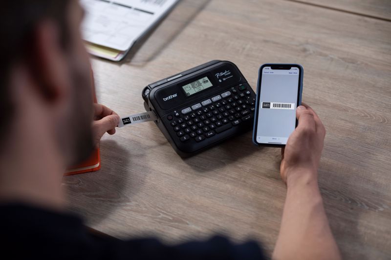 Man printing a barcode from a Brother P-touch label printer that's connected to a smartphone