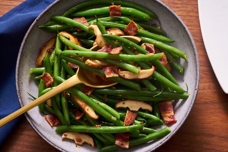 A bowl of bacon and green beans sits on a table