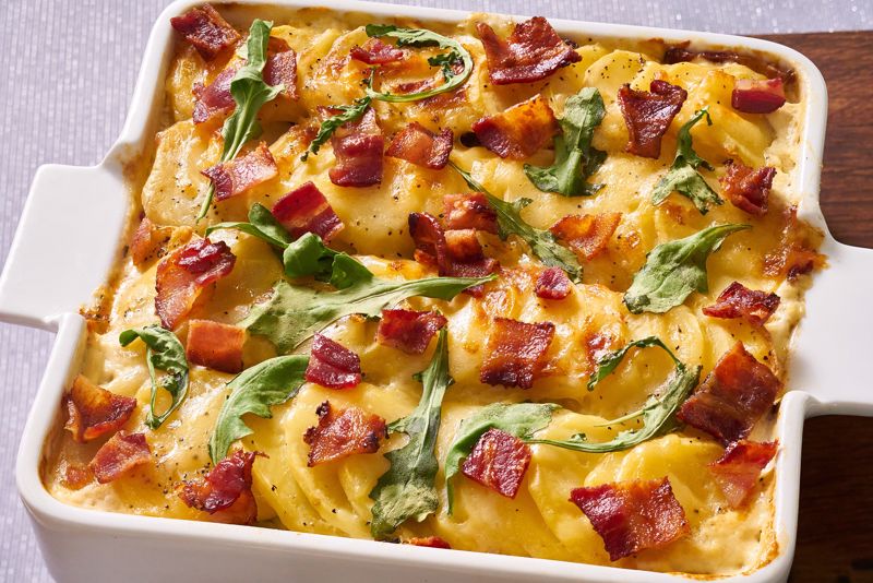 A baking dish with bacon potatoes and arrugula