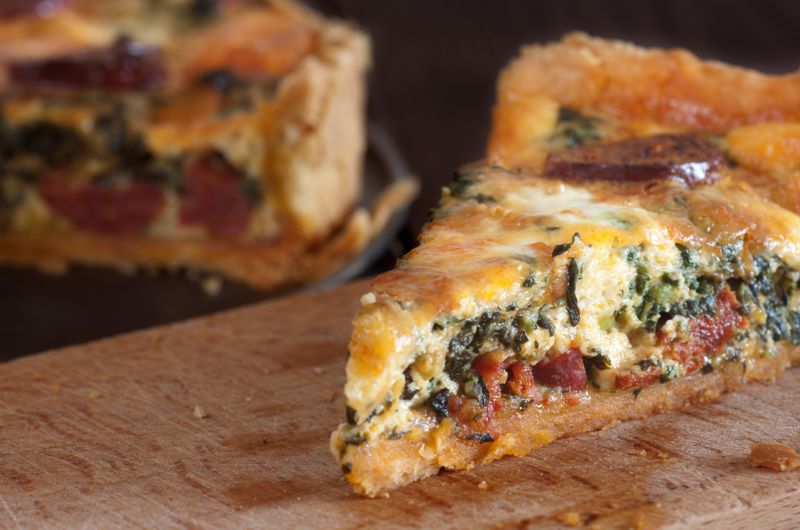A slice of breakfast quiche sits on a table