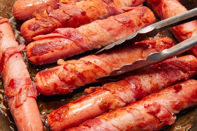 Bacon-wrapped hot dogs on the grill