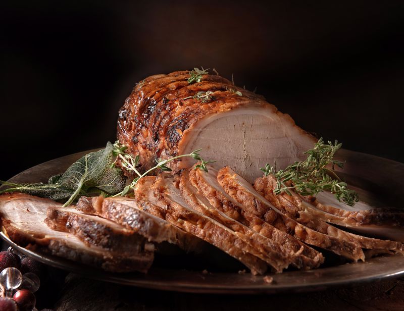A grilled and sliced pork loin roast sits on a table
