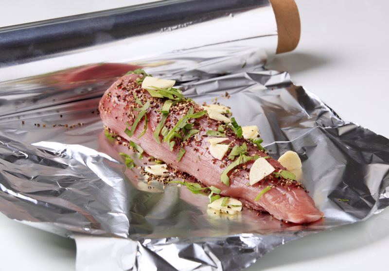 Raw pork tenderloin sits on foil