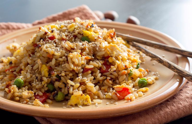 A plate of fried rice with chopstix sits on a table