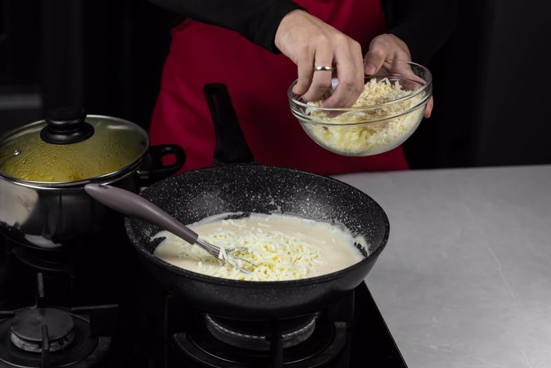 A chef prepares mac and cheese on the stove