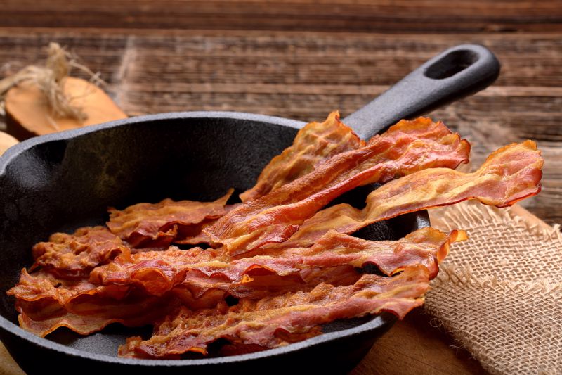 Cooked bacon sits in a cast iron skillet